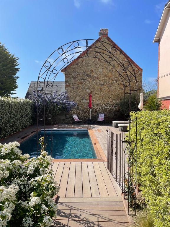 a swimming pool with an archway next to a building at La Cotentine Maison d'Hôtes in Saint-Pair-sur-Mer