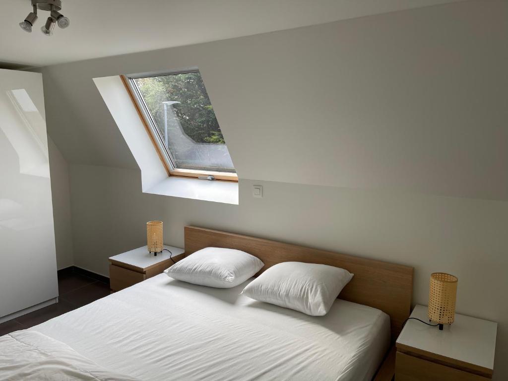 a bedroom with a bed with two pillows and a window at Casa Vista Verde in De Panne