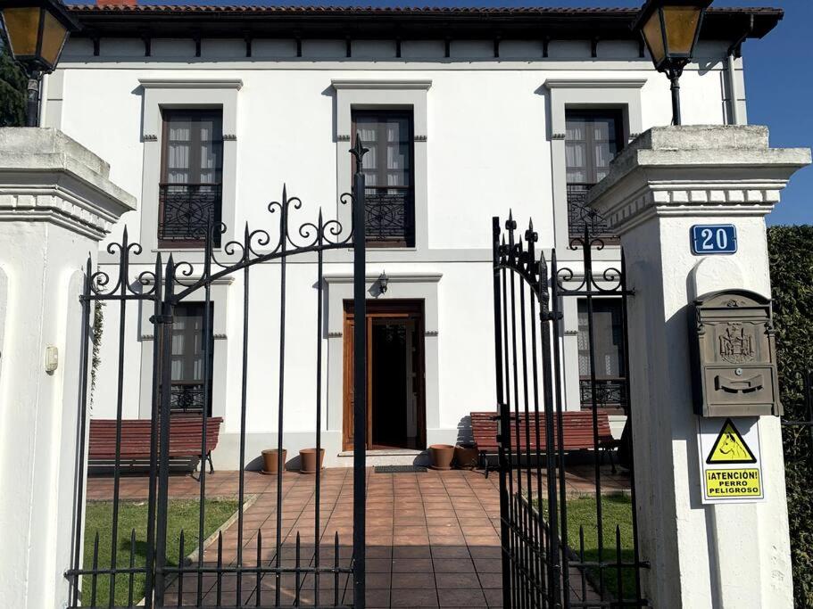 a white building with a gate with benches in front of it at La Casona de Barganaz in Ranón