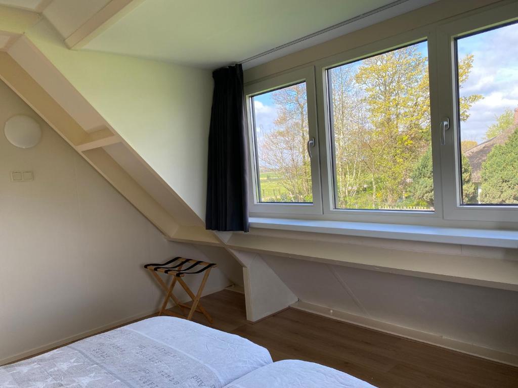 a bedroom with two windows and a bed and a staircase at Appartement Zandwerven 23 in Spanbroek