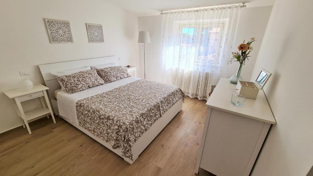 ein weißes Schlafzimmer mit einem Bett und einem Fenster in der Unterkunft Nel cuore di Santa Maria degli Angeli in Santa Maria degli Angeli