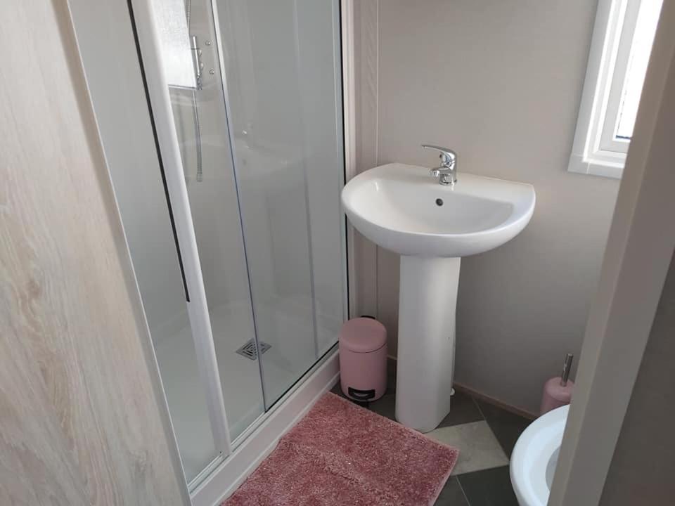 a white bathroom with a sink and a shower at Caravan By The Sea in Elgin