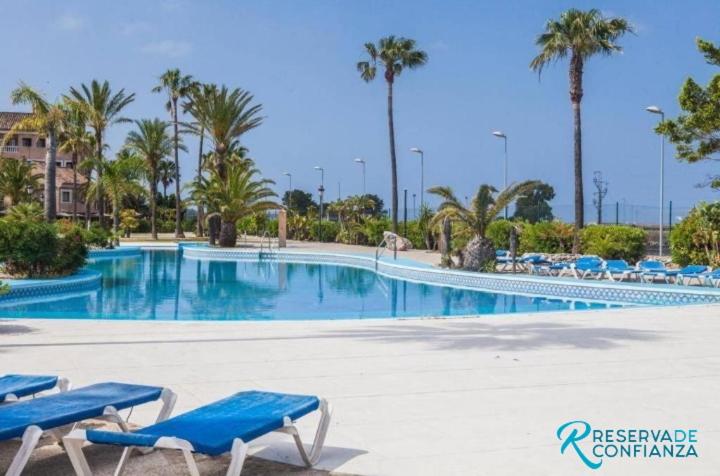 uma grande piscina com cadeiras azuis e palmeiras em APTO BAHIA SUR RESERVA DE CONFIANZA em San Fernando