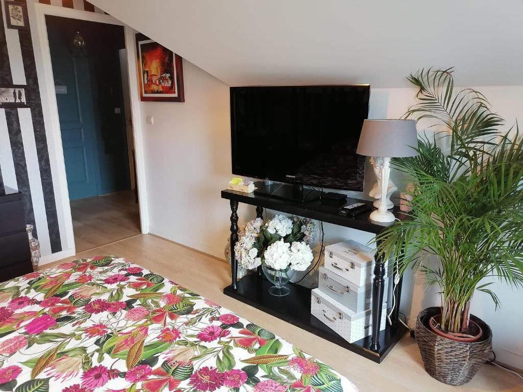 ein Wohnzimmer mit einem Flachbild-TV und Pflanzen in der Unterkunft CHEZ HÉLÈNE in Saint-Coulomb