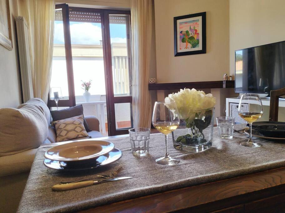 una mesa con copas de vino y flores. en Appartamento Le Rose, en Viareggio