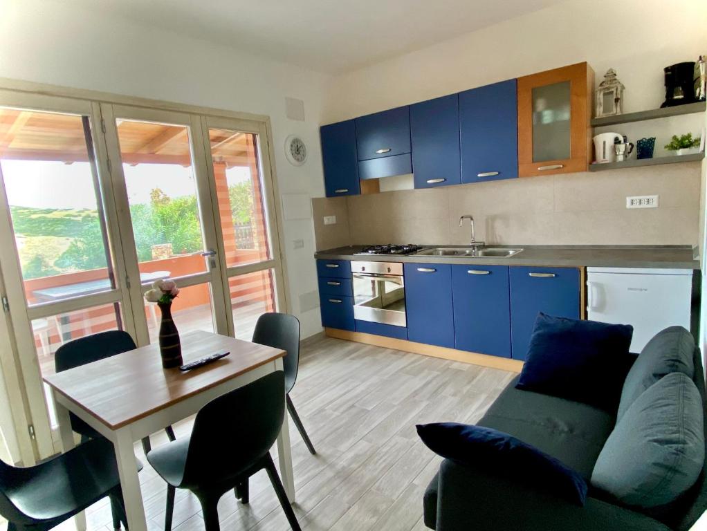 een woonkamer met een tafel en een keuken met blauwe kasten bij Torre dei Corsari APPARTAMENTO CON GIARDINO VISTA MARE in Torre Dei Corsari