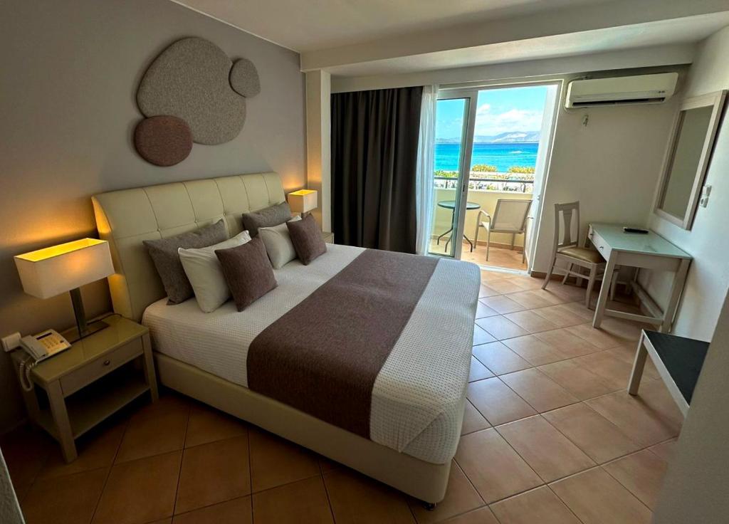 a bedroom with a bed and a view of the ocean at Faedra Beach Resort in Agios Nikolaos