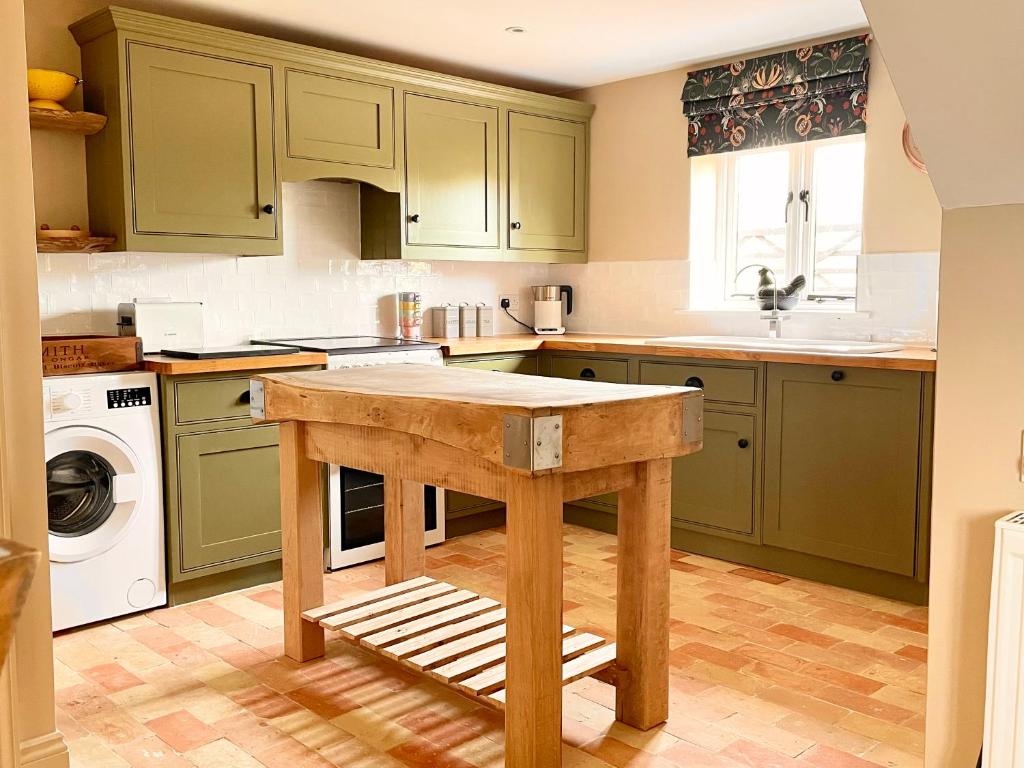 a kitchen with green cabinets and a wooden island at The Hayloft in Gestingthorpe