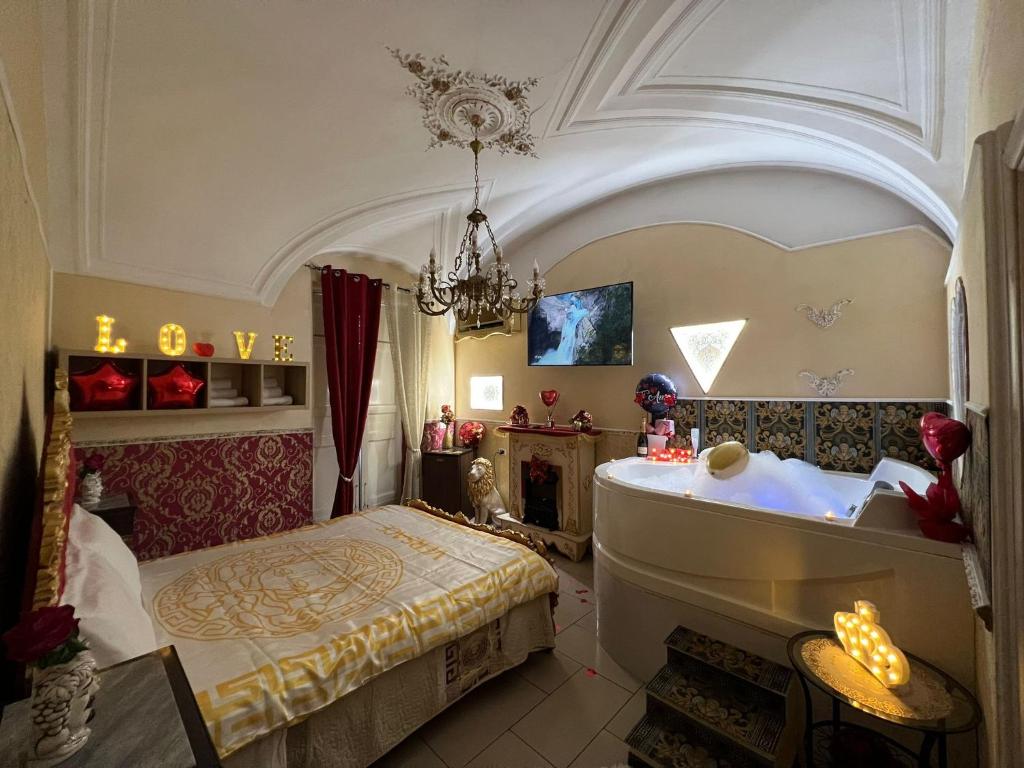 a bedroom with a tub and a bed and a chandelier at B&B Sotto gli archi in Catania