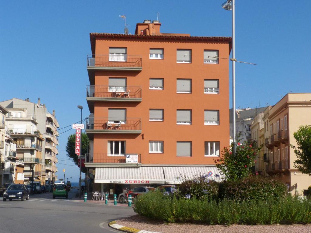 een groot oranje gebouw aan de kant van een straat bij Hostal Zurich in Sant Feliu de Guixols