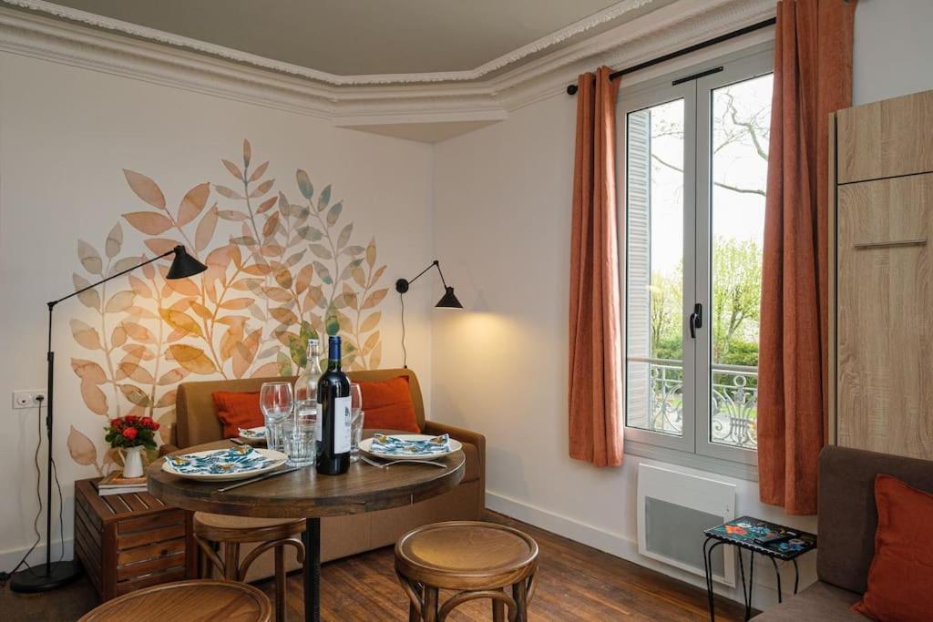 ein Wohnzimmer mit einem Tisch, Stühlen und einem Fenster in der Unterkunft Villa Forestière Studio L'Acacia in Quincy-Voisins