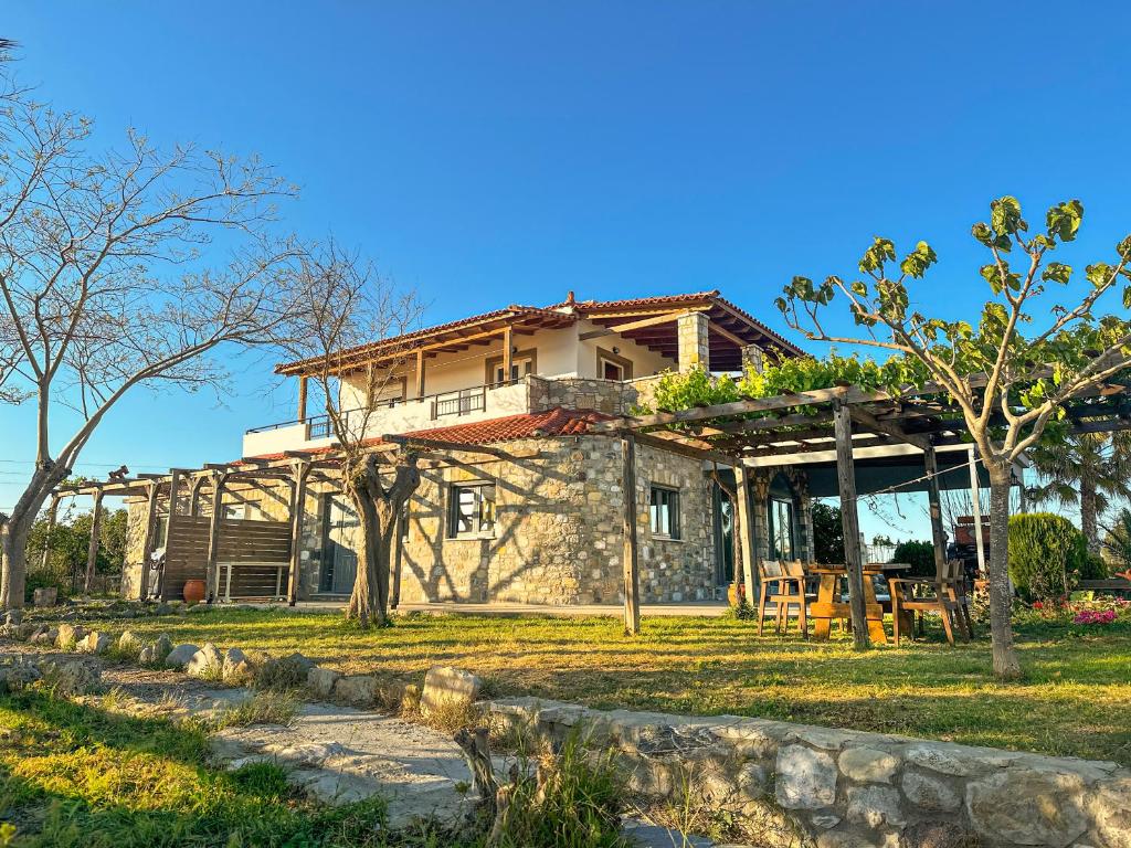 a large stone house with a porch and trees at Casa De Linda in Antimácheia