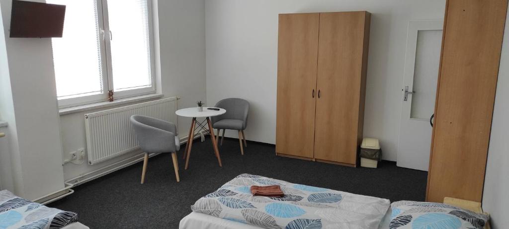 1 dormitorio con 1 cama, mesa y sillas en Penzion Koupaliště, en Litoměřice