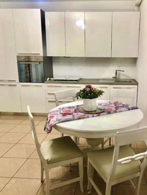una cocina con mesa blanca, sillas y una mesa con flores en Intero appartamento Milano, en Bollate