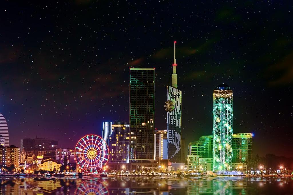 a city skyline at night with a ferris wheel at Apartment Katya in Batumi