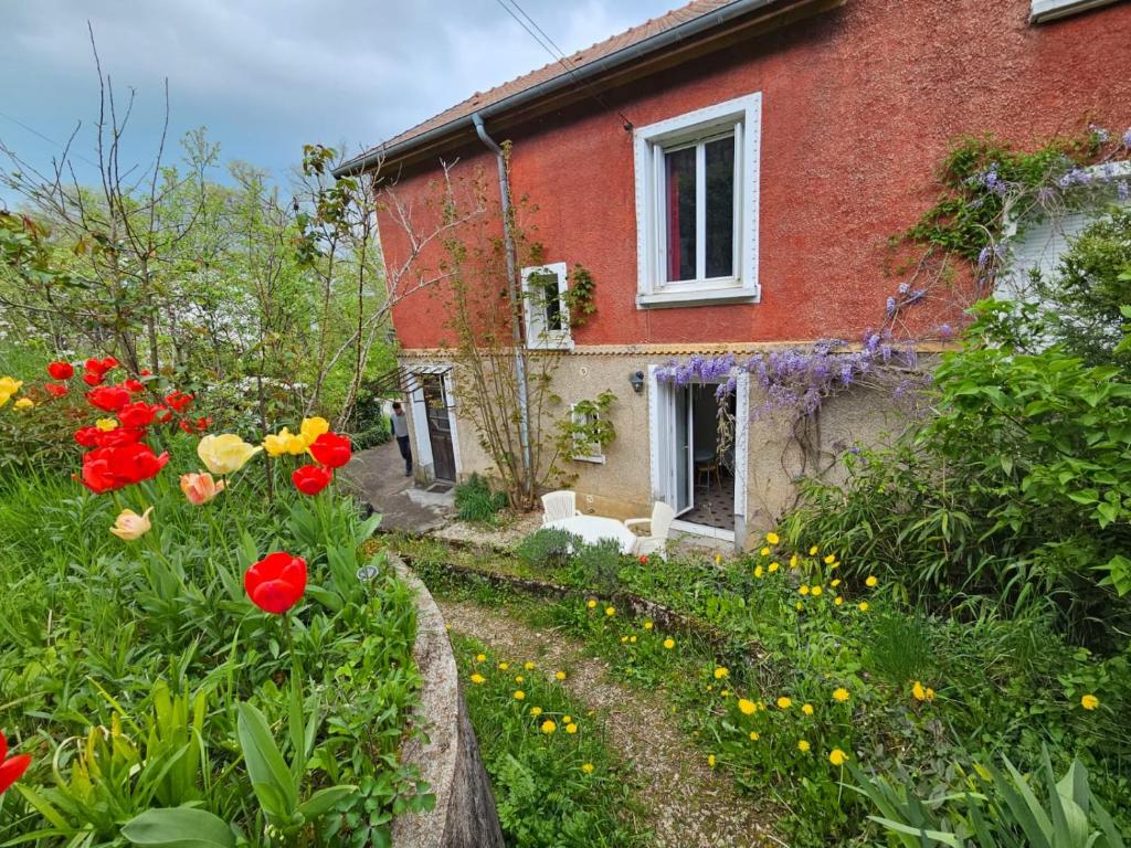 une maison en briques rouges avec des fleurs devant elle dans l'établissement L'Annexe de la corniche, à Chaumont