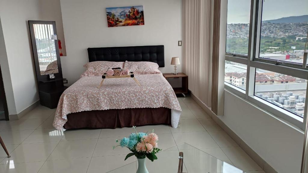 een slaapkamer met een bed en een vaas met bloemen erop bij Suite Ejecutiva en excelente ubicación con Piscina-Parqueo-Gym-Seguridad 24/7 in Guayaquil