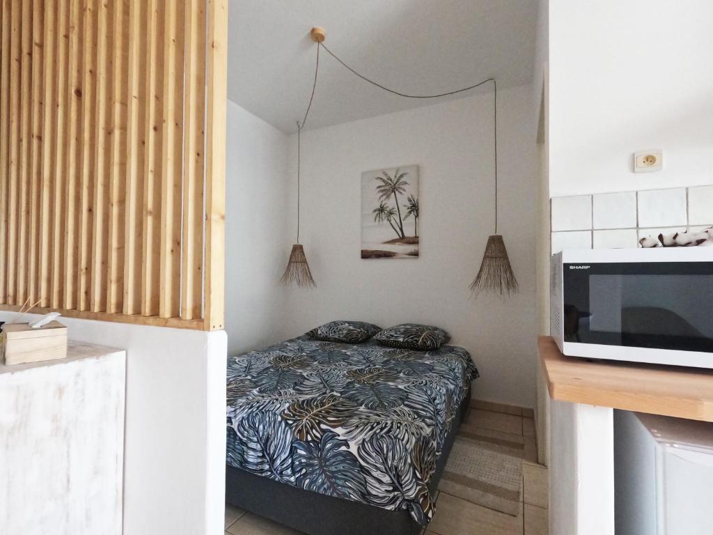 ein kleines Schlafzimmer mit einem Bett und einer Mikrowelle in der Unterkunft Ti cocon in Le Tampon
