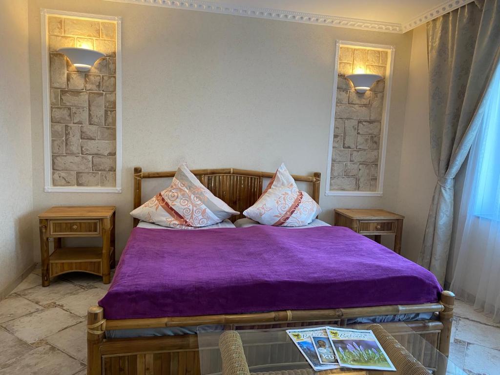 um quarto com uma cama com um cobertor roxo em Griechischer Palast em Rabenau
