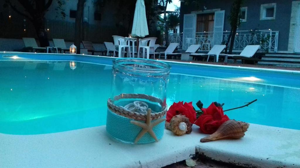 un bocal en verre avec une corde et une étoile de mer à côté d'une piscine dans l'établissement Sun Helios Garden Aparthotel, à Thasos