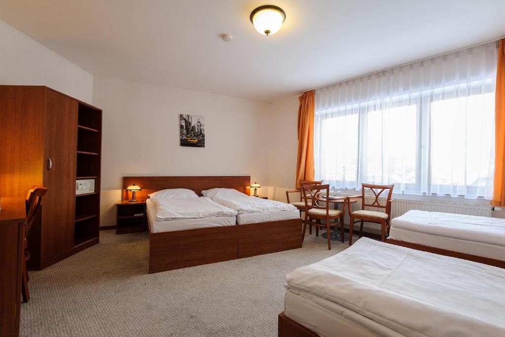 pokój hotelowy z 2 łóżkami, stołem i krzesłami w obiekcie Alexis w Pradze