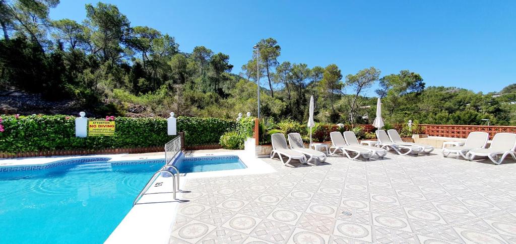 a group of lounge chairs and a swimming pool at Granada Apartments Familiar Deluxe in Portinatx