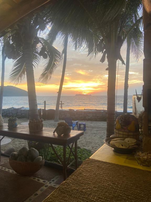 Blick auf den Sonnenuntergang von einem Strand mit Palmen in der Unterkunft Ocean Front Paradise in Petatlán