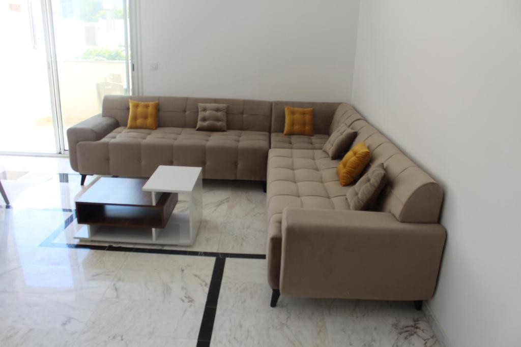 ein Wohnzimmer mit einem braunen Sofa und einem Tisch in der Unterkunft Relaxing Vacation Stay in Mahdia in Rejiche