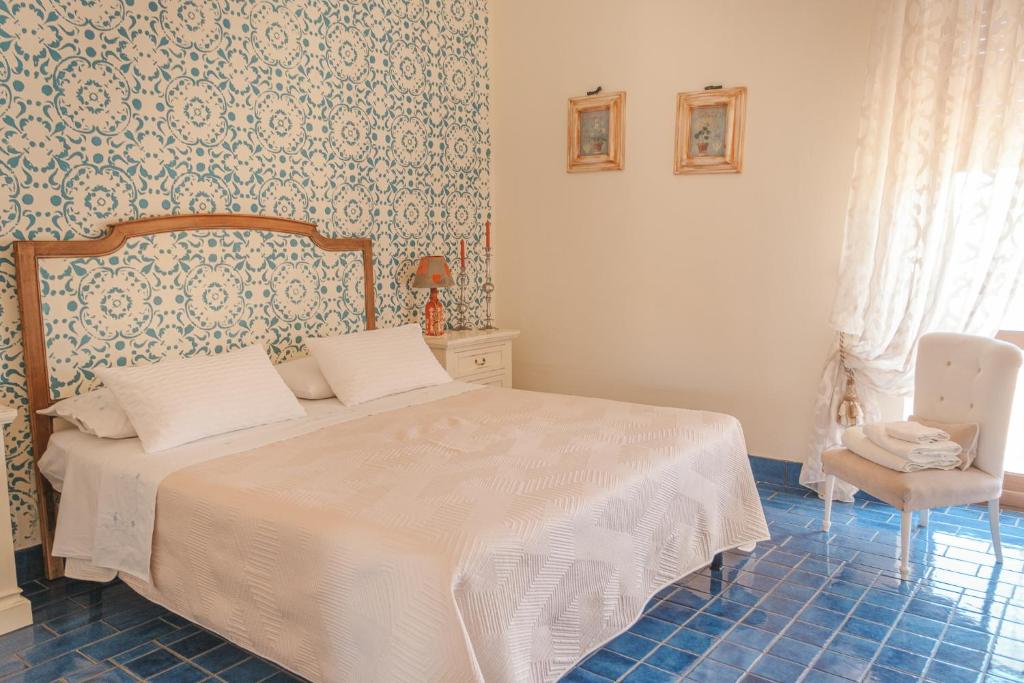 a bedroom with a white bed and a chair at La casa nel borgo in San Nicola Arcella