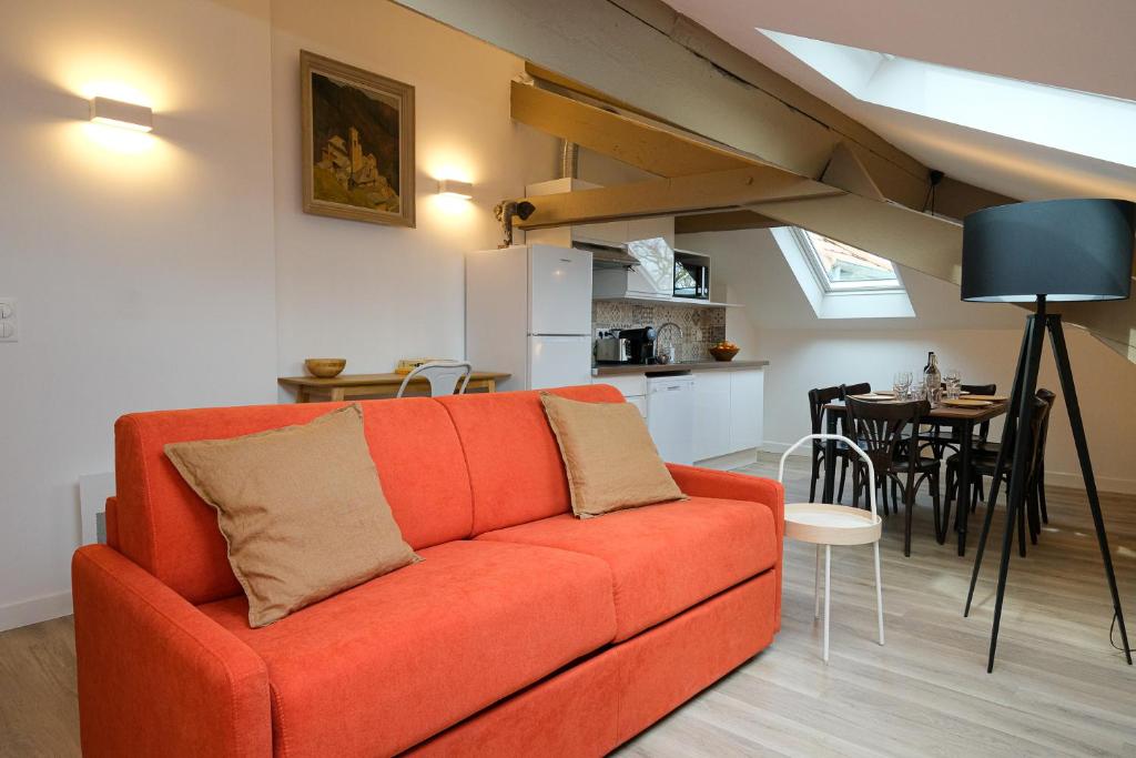 a living room with an orange couch and a kitchen at Villa Forestière Appart Le Cèdre in Quincy-Voisins