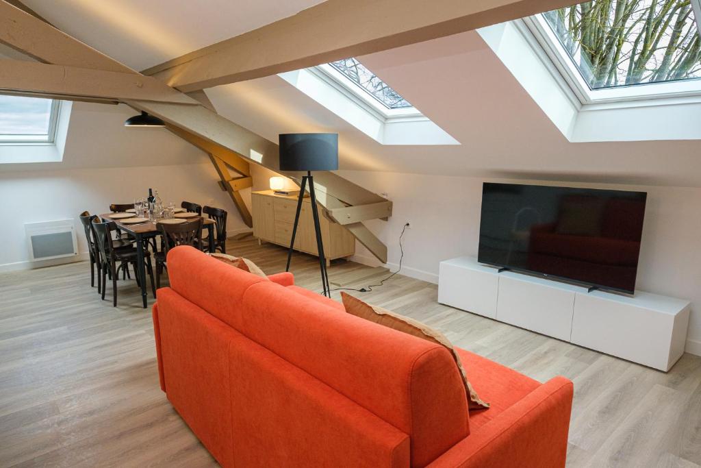 salon z pomarańczową kanapą i telewizorem w obiekcie Villa Forestière Appart Le Cèdre w mieście Quincy-Voisins