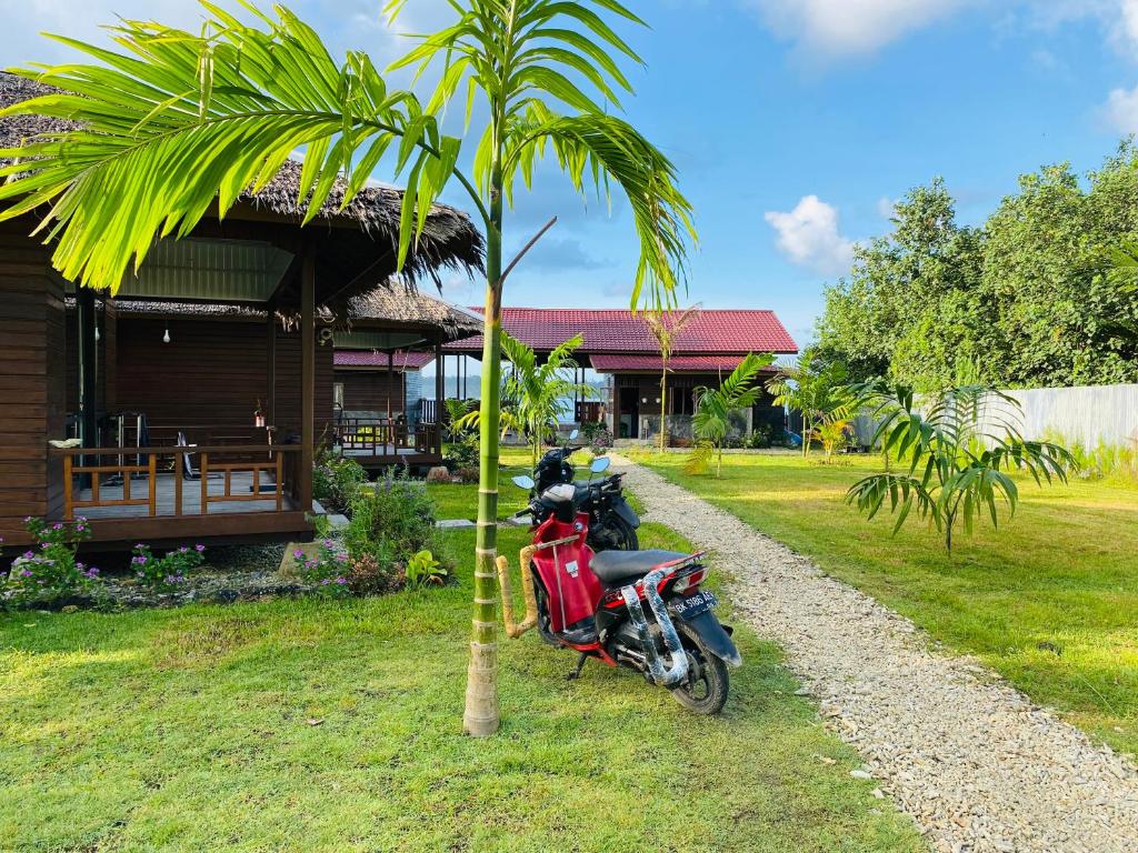 uma moto vermelha estacionada ao lado de uma palmeira em Surge Surf Villas em Lasikin