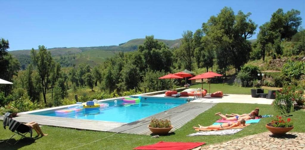 a group of people laying in the grass by a pool at Casa da Pedra - Turismo Rural in Bragado