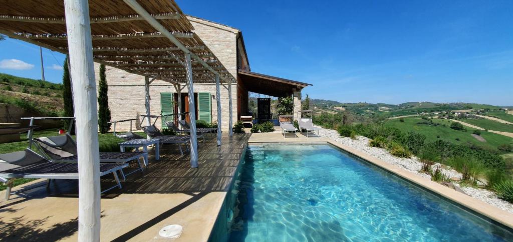 a swimming pool with chairs and a house at Lemonvilla - Rustico in Panoramalage in Castignano