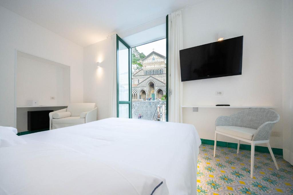 a white bedroom with a large bed and a window at Terrazza Duomo in Amalfi