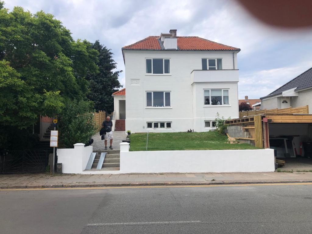 una persona parada frente a una casa blanca en Stor lys lejlighed med terrasse og altan, en Helsingør
