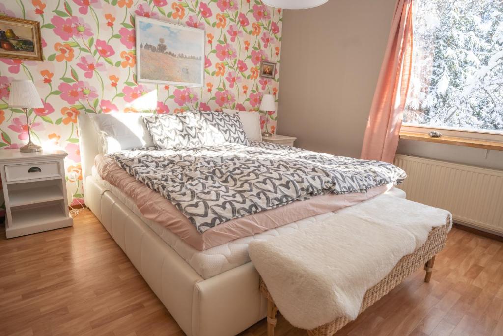 1 dormitorio con cama y papel pintado de flores en A cozy house close to nature en Espoo