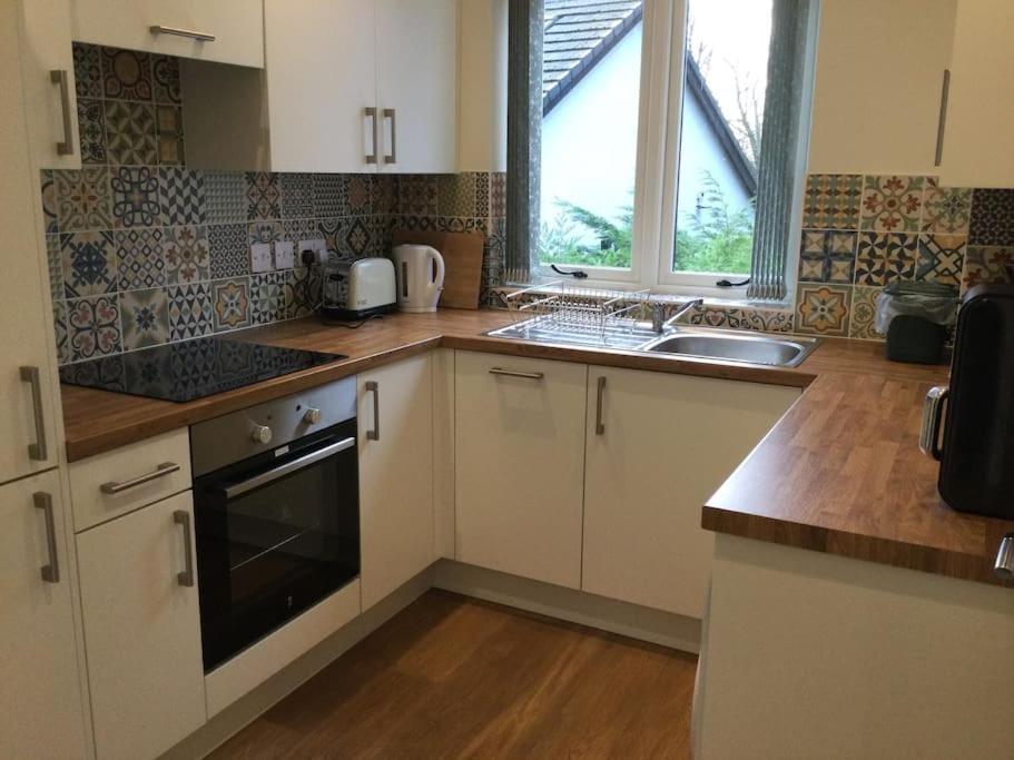 a kitchen with white cabinets and a sink and a window at ChurstonBnB, private flat within family home, Bolton in Lostock