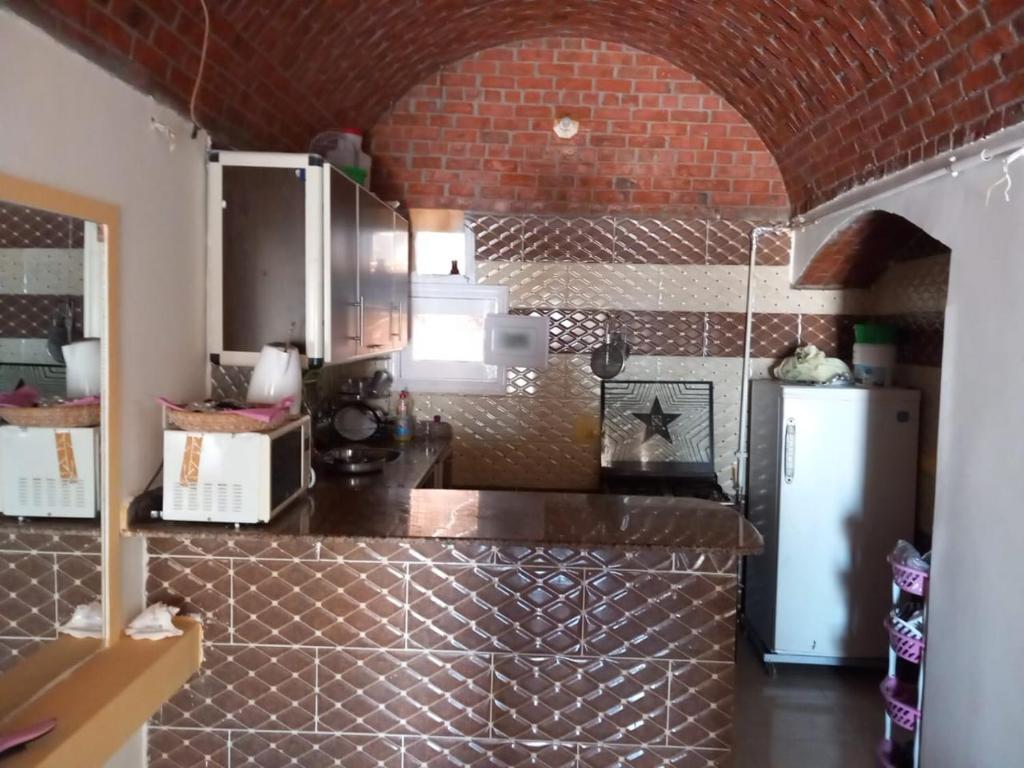 een keuken met een bakstenen muur en een koelkast bij Merit Roof Apartment in Hurghada