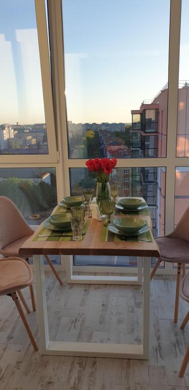 una mesa con platos y flores en el balcón en Dream town Apartaments біля залізничного вокзалу en Lutsʼk