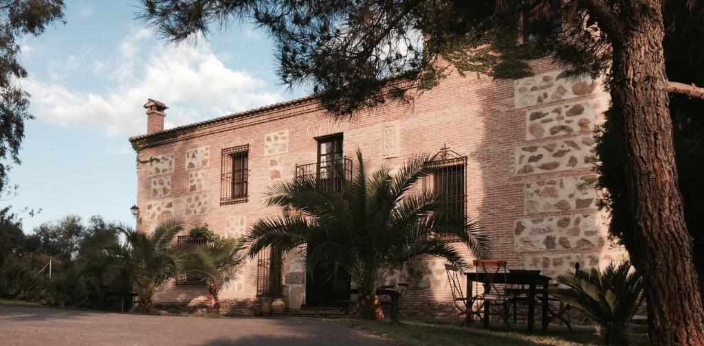 a large brick building with a palm tree in front of it at Casa Rural Rincón de la Fuente in Buenaventura