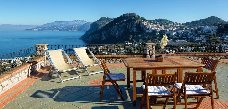 a wooden table and chairs on a patio overlooking the water at Aiano Bed&Breakfast in Capri