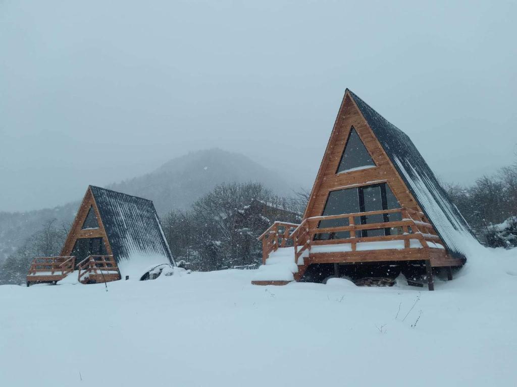 un gruppo di tre case triangolari nella neve di Cabins Tvishi Near Khvamli Mountain a Tvishi