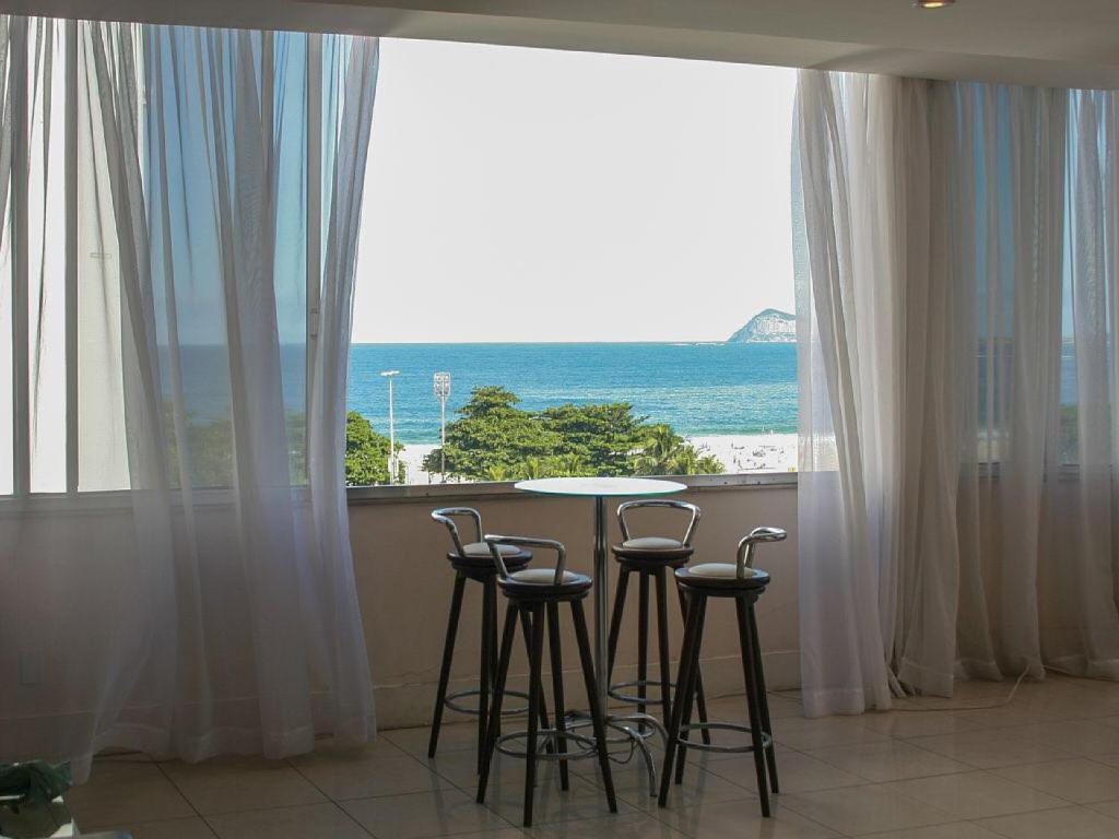 a table and chairs in a room with a view of the ocean at Luxo in copacabana in Rio de Janeiro