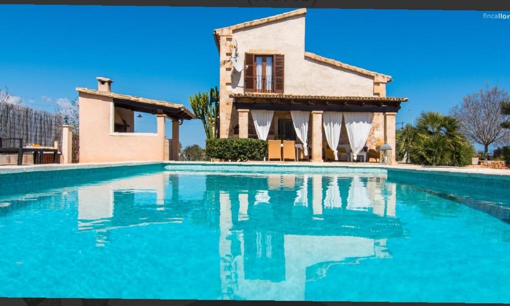 a villa with a swimming pool in front of a house at Finca Cari in Can Picafort