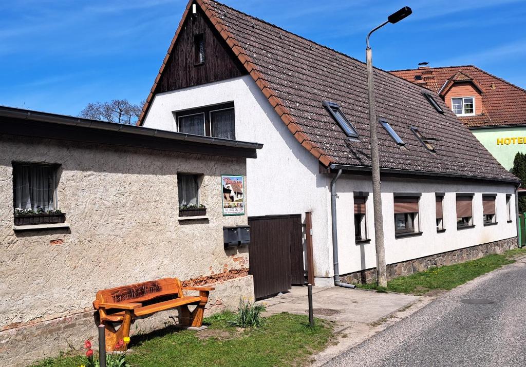 a white building with a wooden bench next to a street at Ferienwohnung Kühl in BooÃŸen