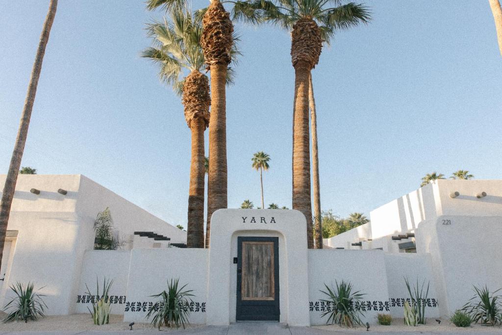 a white building with palm trees in the background at Yara Hotel - Adults Only in Palm Springs