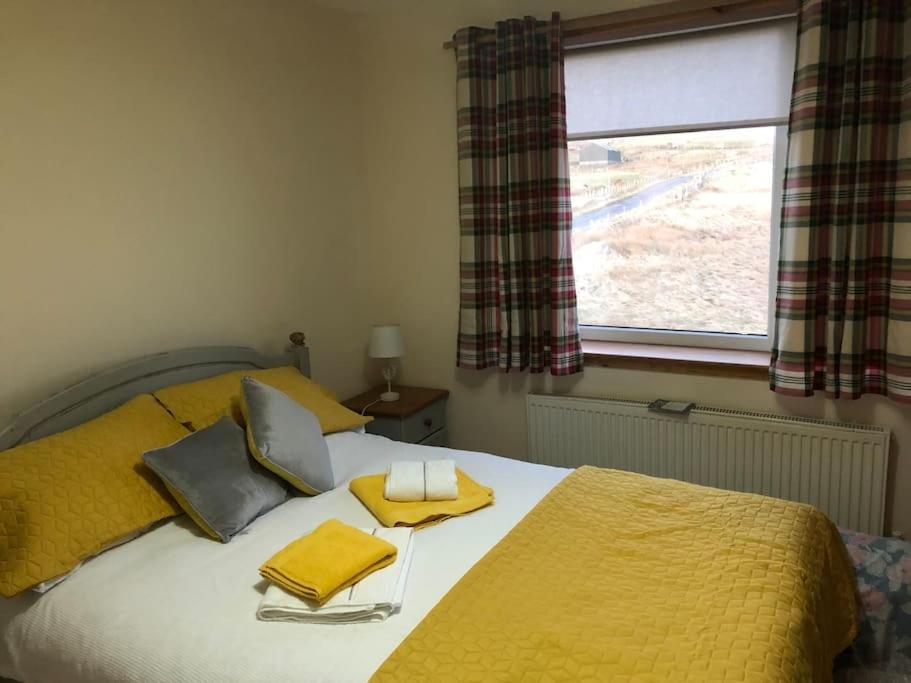 a bedroom with a bed with yellow sheets and a window at Millstreasm in Pollachar
