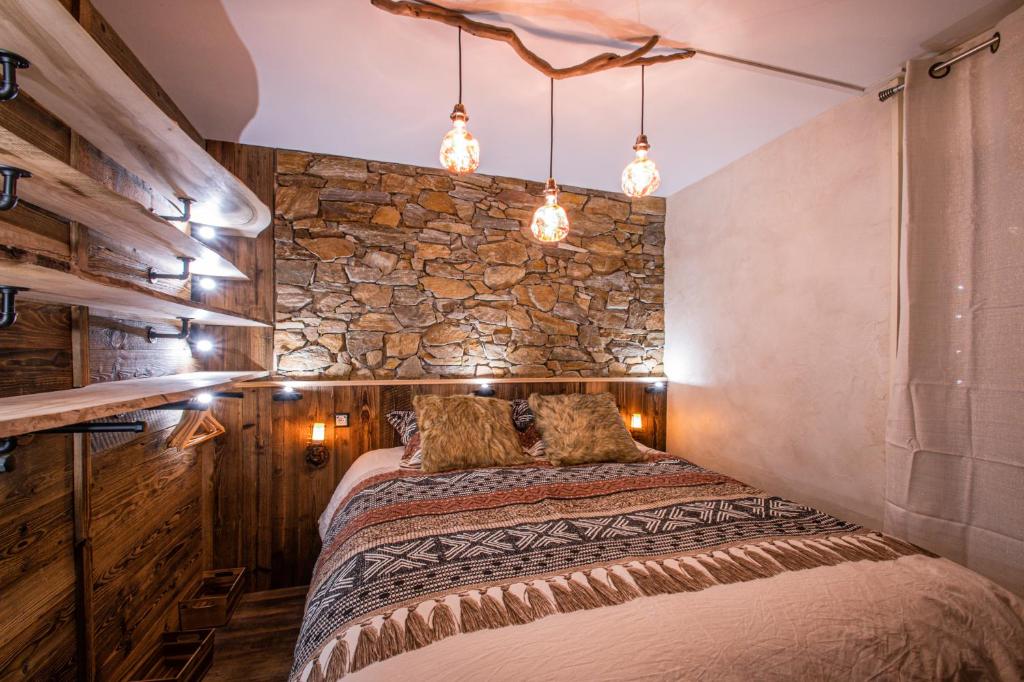 孔布盧的住宿－Le GoOfy, Centre, Navettes pistes ski Combloux，一间卧室设有一张床和石墙