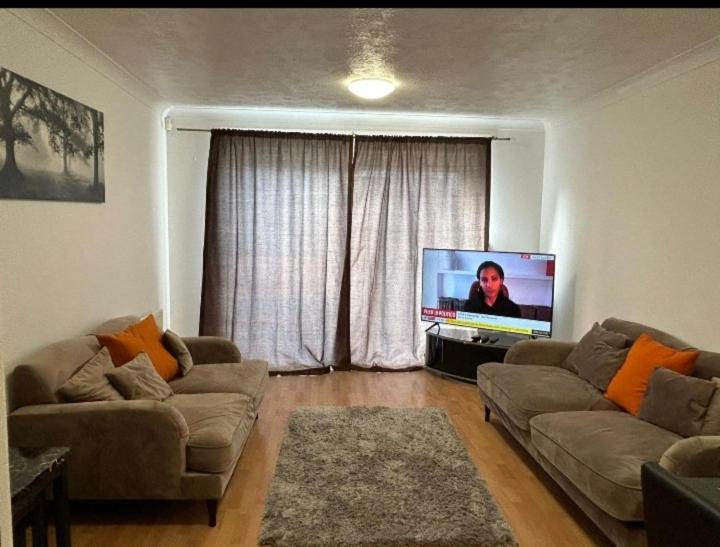 a living room with two couches and a flat screen tv at Gracelink in Erith